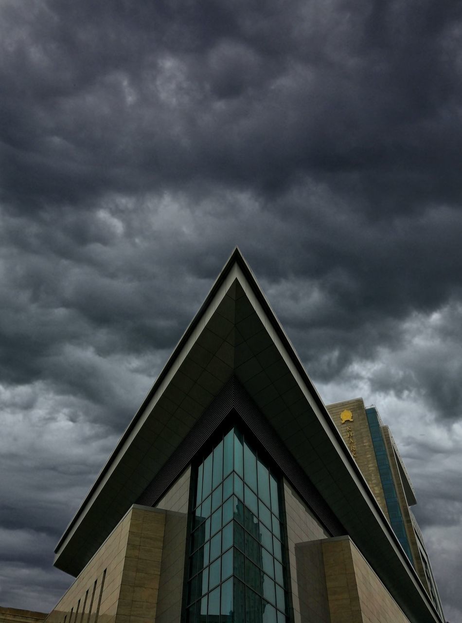 LOW ANGLE VIEW OF BUILDING AGAINST STORM CLOUDS