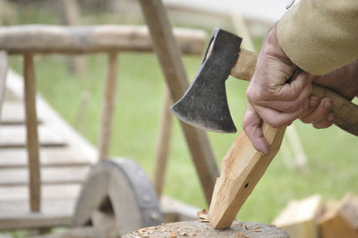 Midsection of carpenter cutting wood on tree stump