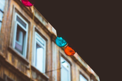 Low angle view of illuminated lanterns hanging by building