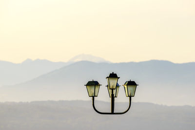 Lamp post against mountains during sunset