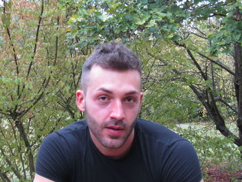 Portrait of young man against trees in forest