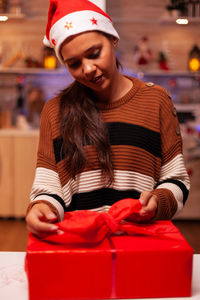 Young woman holding christmas gift at home