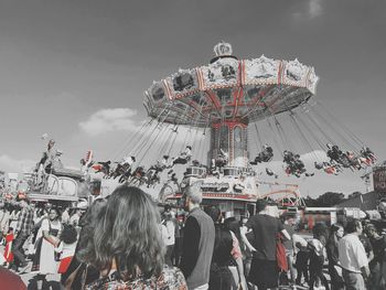 People in front of ferris wheel against sky