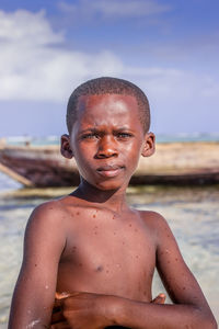 Portrait of shirtless boy at beach against sky