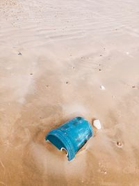 High angle view of blue plastic barrel on sand