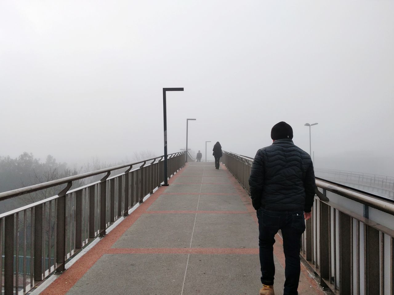 rear view, fog, real people, one person, lifestyles, men, railing, nature, sky, full length, standing, direction, architecture, leisure activity, copy space, the way forward, walking, outdoors, warm clothing