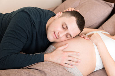 Midsection of man lying on bed at home