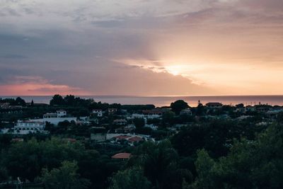 Scenic view of townscape by sea against sky at sunset