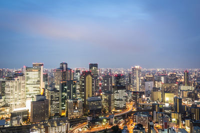 High angle view of city lit up against sky