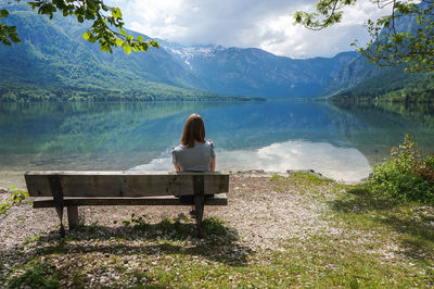 Rear view of woman looking at lake against mountain range