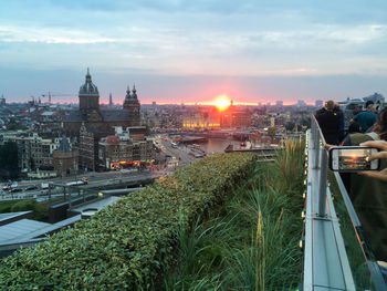 Cropped image of person photographing cityscape during sunset