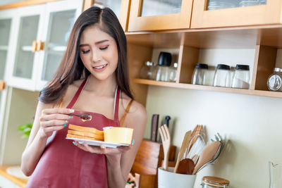 Young woman holding food while standing at home