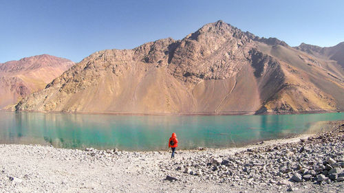 Rear view of man on shore by lake against sky