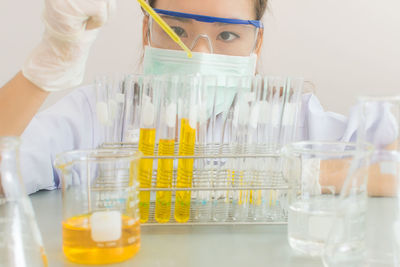 Close-up of scientist pouring liquid in test tube with pipette