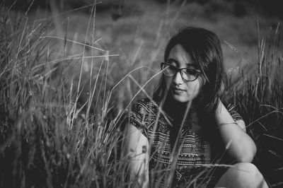 Young woman sitting amidst grass on field