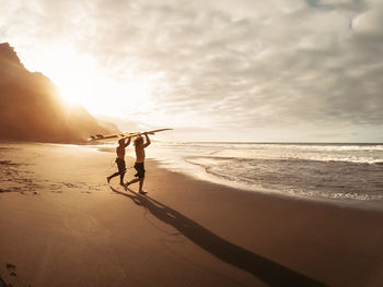 People on beach against sky during sunset