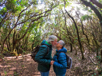 Senior couple kissing while standing in forest