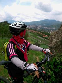 Woman with bicycle on mountain against sky