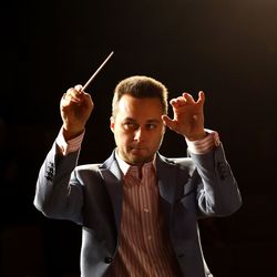 Musician looking away while standing against black background