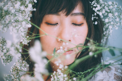 Close-up of woman with eyes closed wearing white flowers