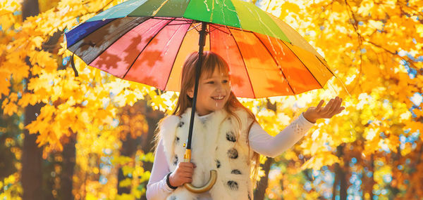 Cute girl holding umbrella at autumn forest