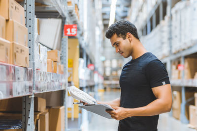 Side view of young man looking up against building
