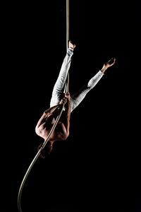 Young man doing gymnastics against black background