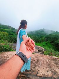 Midsection of person hand on land against sky