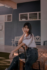 Portrait of young woman sitting on chair at home