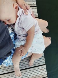 Low section of mother with baby sitting on pier