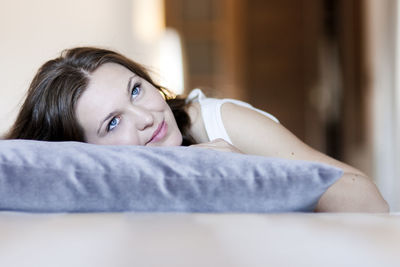 Portrait of young woman lying down at home