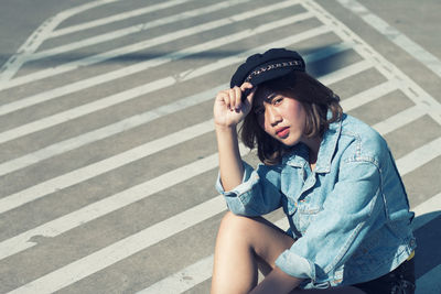 Portrait of young woman sitting on zebra crossing in city