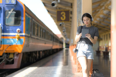 A teenage woman wearing headphones listening to music from an app on a tablet.