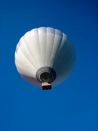Low angle view of hot air balloon flying against clear blue sky