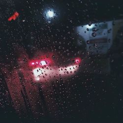 Close-up of wet window against sky at night