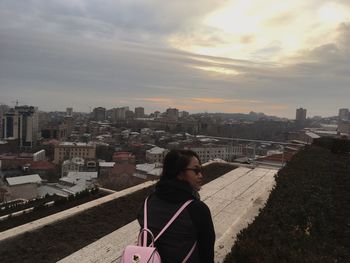 Woman looking at cityscape against sky