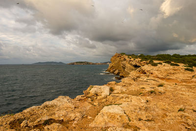 Rock formation on beach against sky