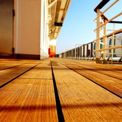 Surface level of wooden walkway against clear sky