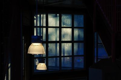 Illuminated lamp hanging on window at home