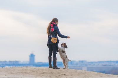 Woman standing with dog on hill against sky