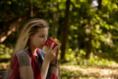 Young woman drinking water while standing outdoors