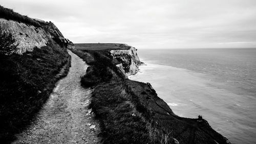 Street on cliff by sea against sky