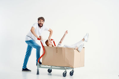 Man pushing cart with woman in box