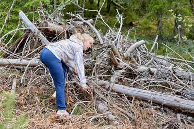 Full length of woman standing on log in forest