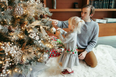 Father and daughter decorating christmas tree at home