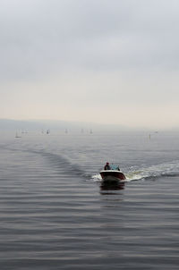 Boat sailing in sea against cloudy sky during foggy weather