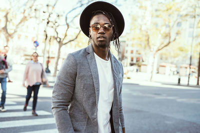 Portrait of young man wearing sunglasses standing on street in city