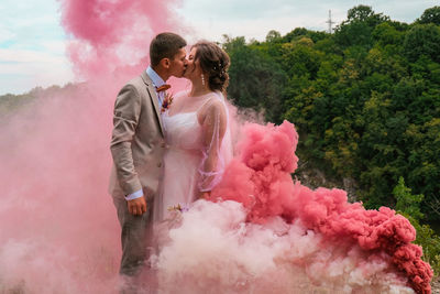 Couple standing amidst pink flowers