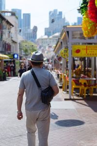 Rear view of person walking on street against buildings