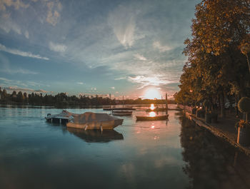 Boats moored in canal against sky during sunset